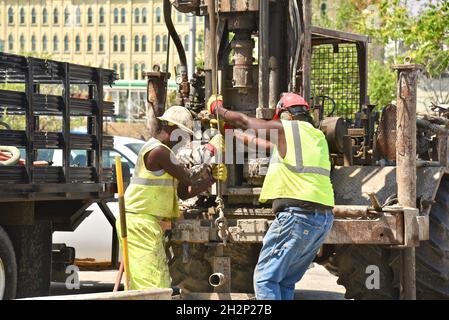 Zwei afroamerikanische Bauarbeiter bohren sicher ein Loch im Stadtzentrum, das an den Wisconsin River, Urban Renewal, Milwaukee, Wisconsin, USA, angrenzt. Stockfoto