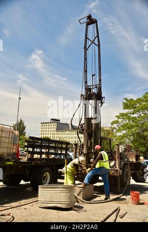 Zwei afroamerikanische Bauarbeiter bohren sicher ein Loch im Stadtzentrum, das an den Wisconsin River, Urban Renewal, Milwaukee, Wisconsin, USA, angrenzt. Stockfoto