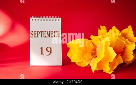 Kalender mit dem Text Oktober 19 auf rotem Hintergrund und mit Ahornblatt Stockfoto