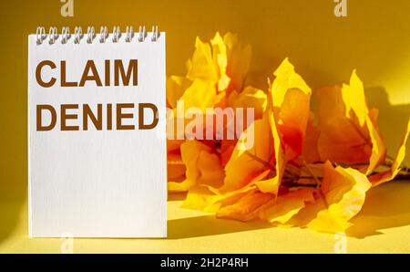 Der Satz, der abgelehnt wurde, steht auf einem Notizbuch und einem gelben Tisch mit Laub im Hintergrund. Stockfoto
