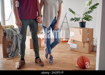Detail, abgeschnitten Bild von jungen Paar Hände in neue Wohnung mit ausgepackten Boxen um sie halten Stockfoto