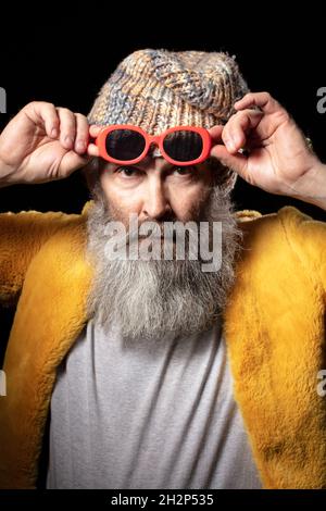 Vertikales Porträt eines älteren Mannes in modischer Kleidung und roter Brille. Stockfoto