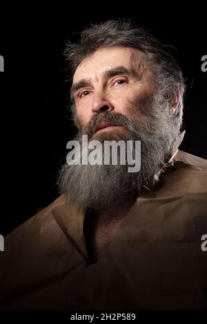 Ein lustiges Porträt eines älteren Mannes mit einem Renaissance-Bart, eingewickelt in Papier. Stockfoto