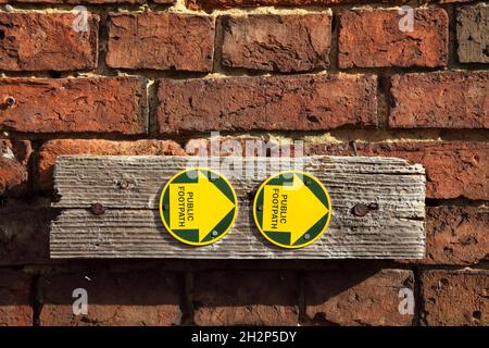 Öffentliche Fußpfadschilder an der Backsteinmauer. Stockfoto