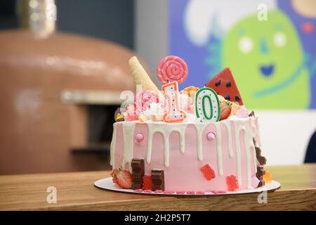 Geburtstagskuchen Nummer 10. Kerze auf Kuchen mit Süßigkeiten verziert Stockfoto