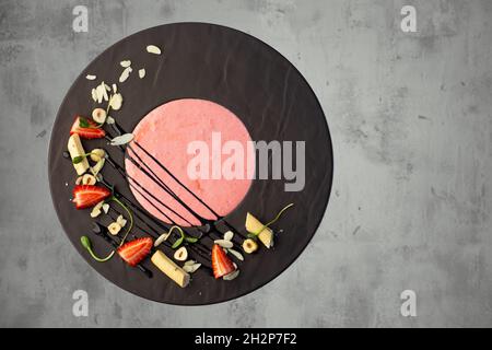 Erdbeersahnensuppe mit Schokolade, Käse und Erdbeere auf grauem Hintergrund. Stockfoto