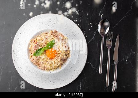 Pasta Carbonara. Spaghetti mit Speck, Parmesan, Sahnesauce und Eigelb auf schwarzem Marmorboden. Mediterrane Gourmetküche. Stockfoto