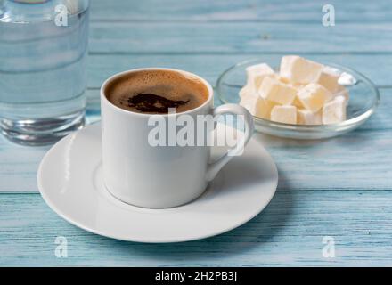 Duftender türkischer Kaffee, ein Glas Wasser und türkischer Genuss auf einem Holztisch. Stockfoto
