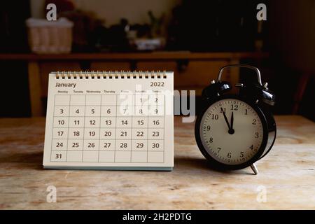 Januar 2022 Kalender und schwarze Vintage-Uhr auf Holztisch Stockfoto