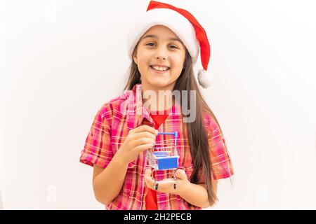 Aufnahme eines kleinen Mädchens, das Geschenke in einem Mini-Einkaufswagen auf weißem Hintergrund schiebt Stockfoto