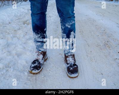 Die Beine des Mannes in braunen Stiefeln bleiben im Schnee Stockfoto