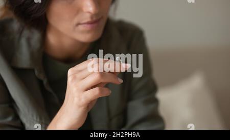 Depressive traurige junge Frau, die auszieht und den Ehering hält Stockfoto