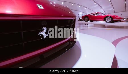 Modena, Italien - 14. Juli 2021: Silbernes, tänzeltes Ferrari-Pferd Logo auf Kühlergrill mit dem Red Dino 246GT-Hochleistungssportwagen auf BA Stockfoto
