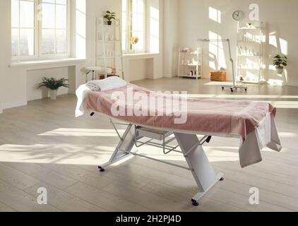 Spezielle Couch für Massage oder kosmetische Eingriffe in der Mitte des hellen Schönheitssalons. Stockfoto