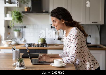 Glückliche freiberufliche Frau, die von zu Hause aus am Computer arbeitet Stockfoto