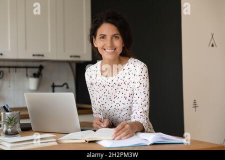 Glückliche Studentin mit Laptop und Notebooks, die online studiert Stockfoto