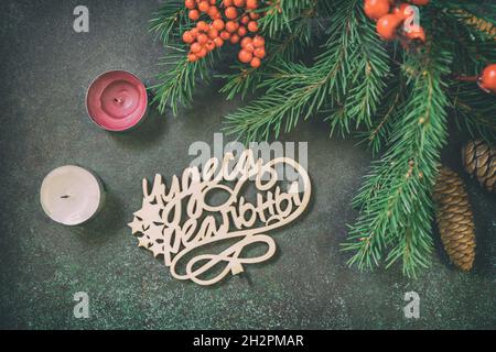 Weihnachtliche Wohnung mit Tannenzweig, Kerzen und Weihnachtsschmuck auf einem dunkelgrünen Steinhintergrund. Stockfoto