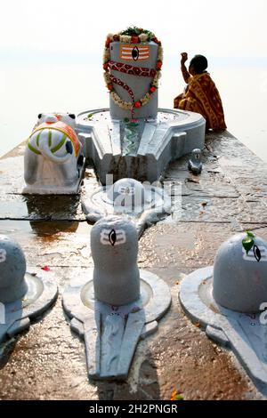 INDIEN. EINE FRAU MACHT EINE PUJA AM UFER DES GANGES ZUM SCHWULEN GHAT IN VARANASI (BENARES) Stockfoto