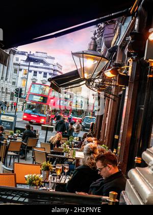 IM FREIEN NACH DER ARBEIT TRINKEN STRASSE geschäftigen Winter London Szene bei Sonnenuntergang Abenddämmerung mit roten Bus Pendler und typischen Pub im Vordergrund der Strand London WC2 Stockfoto