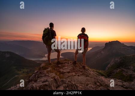 Reisen Sie in die Alpen, Touristen Wanderer mit Rucksäcken bei Sonnenuntergang genießen Panoramablick