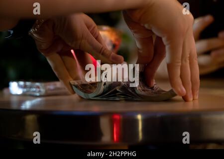 Nahaufnahme von Mädchen Hände shuffling Karten auf einem Tisch in der Nacht. Dunkel und verschwommen Hintergrund Stockfoto