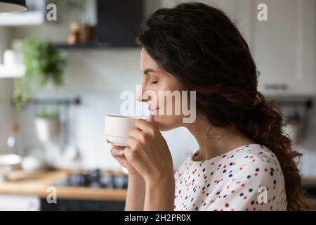 Glückliche, friedliche Frau, die morgens Kaffee in der Küche genießt Stockfoto