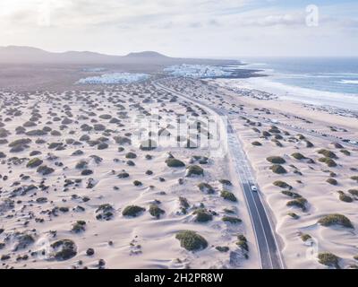 Schöne Straße in Sandwüste an der Küste von Lanzarote, Luftlandschaft der Autofahrten auf den Kanarischen Inseln Stockfoto