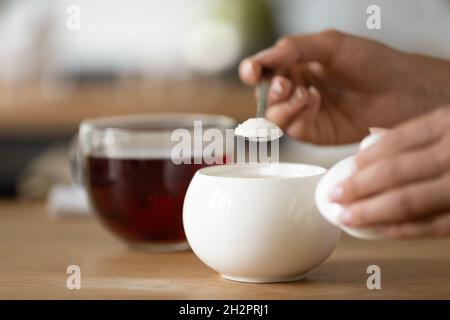 Hände einer Frau, die süßen Tee zubereitet und den Löffel hält Stockfoto