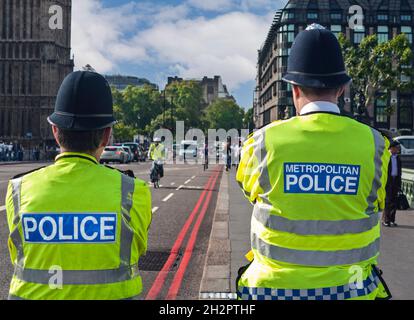 London Metropolitan Police Officers von hinten, tragen traditionelle Helme und gut sichtbare Jacken auf Westminster Bridge rote Sicherheitskontrolle und suchen Street Duty Back Rückansicht, Westminster Bridge Houses des Parlaments London UK Stockfoto