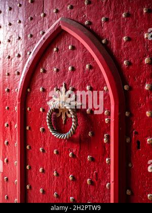 GOTISCHE ROTE NIETEN TÜR & KLOPFER Alte Nieten Tür Gotische historische hölzerne rote Messing verzierte Kirche Eingangstür zu Winchester Cathedral Hampshire UK Stockfoto