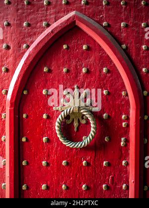 GOTISCHE ROTE NIETEN TÜR & KLOPFER Alte Nieten Tür Gotische historische hölzerne rote Messing verzierte Kirche Eingangstür zu Winchester Cathedral Hampshire UK Stockfoto