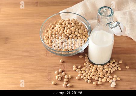 Vegane Milch aus Sojabohnen in einer Glasflasche, Alternative zu tierischen Milchprodukten auf einer Holzplatte mit Kopierfläche, ausgewählter Fokus, geringe Tiefe von f Stockfoto