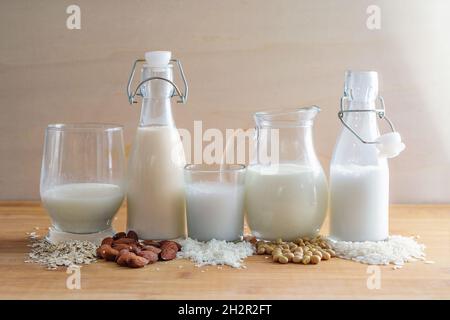 Vegane Milchvariationen aus Getreide und Nüssen in Gläsern und Flaschen mit Zutaten, Alternative zu tierischen Milchprodukten auf einem Holztisch, Kopie Stockfoto