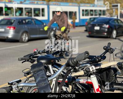 Geparkt mit dem Fahrrad im Stadtzentrum. Im Hintergrund herrscht reger Verkehr mit Autos, Straßenbahnen und einem Mann, der ein Fahrrad fährt. Stockfoto