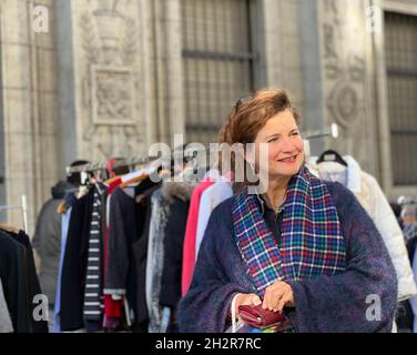 Frau mittleren Alters auf dem Flohmarkt in Zürich. Sie hält ihre Handtasche und lächelt, freut sich über Shopping und Schnäppchen auf dem Markt. B Stockfoto