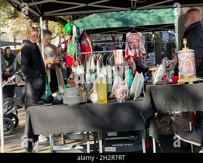 Flohmarkt-Stand mit Vintage-china-Waren. Es gibt potenzielle Kunden, die die Waren inspizieren. Stockfoto