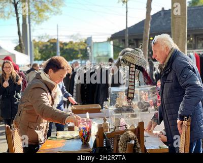 Einkaufen am Flohmarkt in Zürich, Burkliplatz am Samstagnachmittag. Lady verhandelt über den Preis einer Vase. Stockfoto