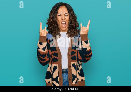 Mittelalter hispanische Frau trägt lässige Kleidung schreien mit verrückten Ausdruck tun Rock-Symbol mit Händen nach oben. Musik-Star. Heavy-Konzept. Stockfoto