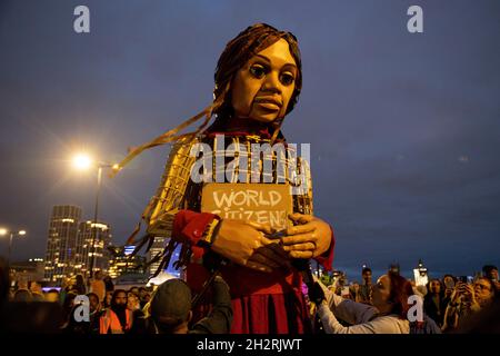 London, Großbritannien. Oktober 2021. Little Amal sah, wie sie ein Plakat mit dem Titel "World Bürger" hielt, das ihr von einem Unterstützer gegeben wurde.Little Amal ist eine 3.5 Meter hohe Marionette, die ein syrisches Flüchtlingskind darstellt, dessen Reise nahe der türkisch-syrischen Grenze begann und 8,000 km quer durch Europa nach Großbritannien zur Unterstützung von Flüchtlingen reiste. Kredit: SOPA Images Limited/Alamy Live Nachrichten Stockfoto