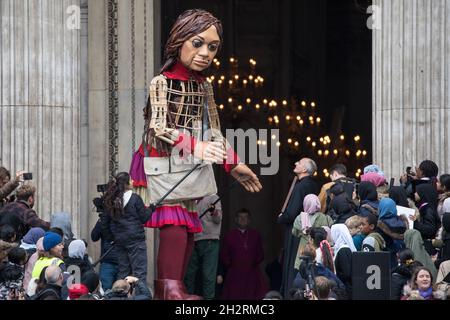 London, Großbritannien. Oktober 2021. Die kleine Amal, eine riesige Marionette eines syrischen Flüchtlingsmädchens, das auf der Flucht vor Konflikten ist, stellt Dr. David Ison, dem Dekan der St. Paul's Cathedral, eine Holzschnitzerei eines Schiffes auf See vor, das vom Geburtsort des heiligen Paulus in Tarsus in der Türkei stammt. Die 3.5 Meter lange Marionette nähert sich dem Ende einer 8,000 km langen Reise von der türkisch-syrischen Grenze nach Manchester zur Unterstützung von Flüchtlingen. Kredit: Mark Kerrison/Alamy Live Nachrichten Stockfoto