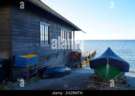 Ein malerischer Blick auf den Ammersee in Herrsching (Deutschland) mit einem Bootshaus und ein paar Booten am Seeufer Stockfoto