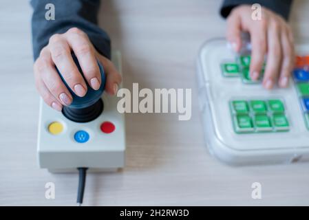 Frau mit zerebraler Lähmung arbeitet an einer spezialisierten Computermaus. Stockfoto
