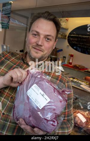 Neu Pudagla, Deutschland. Oktober 2021. Michael Fröhlich, Geschäftsführer der Firma Usedomer Wild, verkauft auf dem Gelände des Forstamtes in Neu Pudagla in der Gemeinde Ückeritz ein Bein Rothirschkalb mit Knochen. Wildfleisch neigt dazu, eine Nische in der deutschen Ernährung zu besetzen. Doch die Händler in Mecklenburg-Vorpommern verzeichnen eine wachsende Nachfrage. Quelle: Stefan Sauer/dpa/Alamy Live News Stockfoto