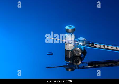 Spritze mit Fläschchen und Nadel auf blauem Hintergrund Stockfoto