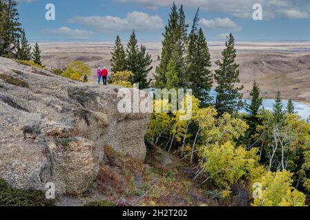 Ein kaukasisches Senior-Paar, das über die Herbstfarben des Konglomerats Cliffs in Cypress Hills, SK, schaut Stockfoto