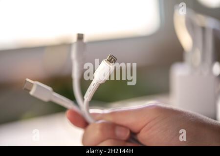 Drei verschiedene Anschlüsse zum Laden eines Mobiltelefons auf unscharfem Hintergrund. Stockfoto