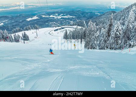 Skifahrer auf der spektakulären Skipiste. Bergbahnen und gefrorener Seeblick von der Skipiste, Poiana Brasov, Karpaten, Rumänien, Europa Stockfoto