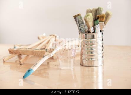 Blechdose mit Pinsel auf einem Werkstatttisch auf unscharfem Hintergrund. Stockfoto