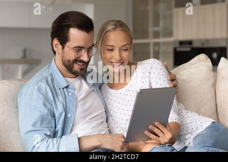 Glückliches, liebevolles Millennial-Familienpaar mit digitalem Tablet. Stockfoto