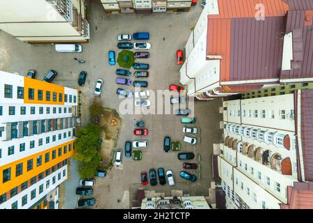 Luftaufnahme von geparkten Autos auf dem Parkplatz zwischen hohen Wohngebäuden. Stockfoto